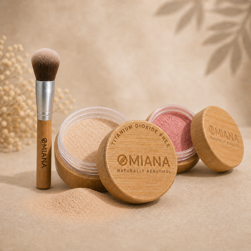 Omiana titanium dioxide free makeup products including a brush, loose powder mineral foundation, and mineral blush on a beige background